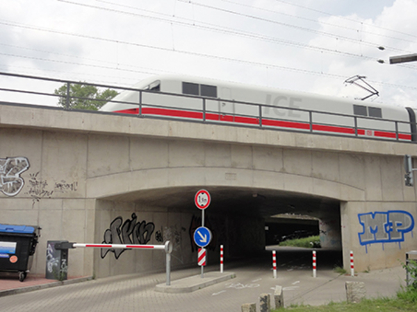 Zu sehen ist eine modernisierte Brücke in Bielefeld, über die ein weißer Zug fährt.